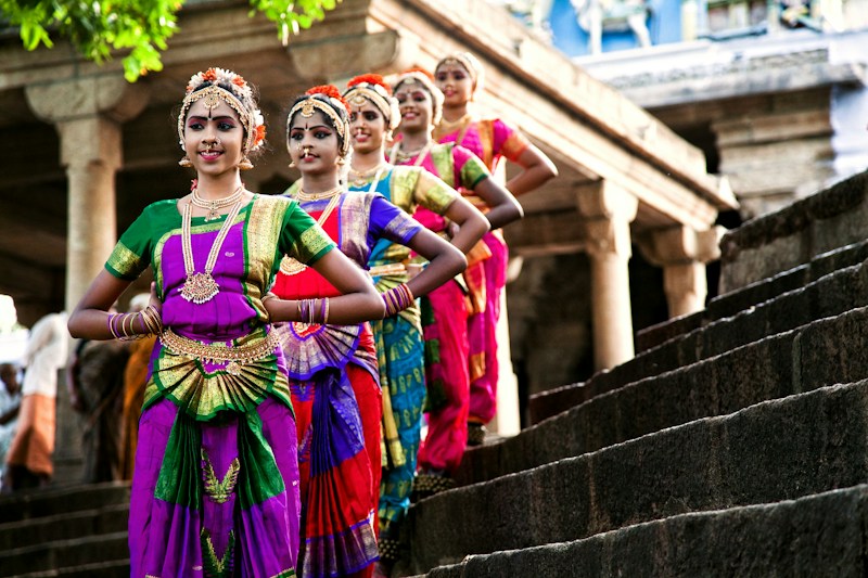 Young Bharatanatyam dancers in silk costumes and jasmine on the steps of a temple