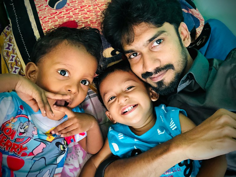A father hugging his two smiling young children close